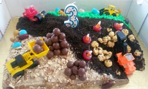 Cake made for construction theme party has crushed oreos, carmel corn rocks, and candy corn orange cones for 'danger'