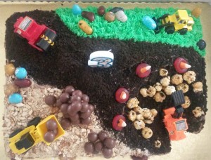 Cake made for 3 year old party with toy trucks, and chocolate goodies on the construction site