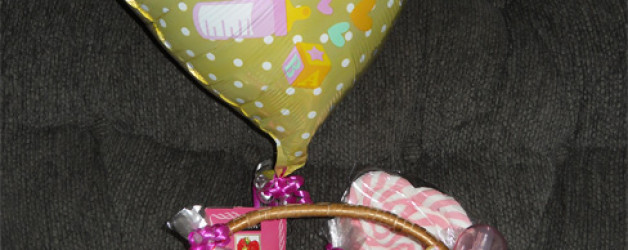 yellow ballon flies over a gift basket of biscotti and treats to celebrate birth - its a girl!