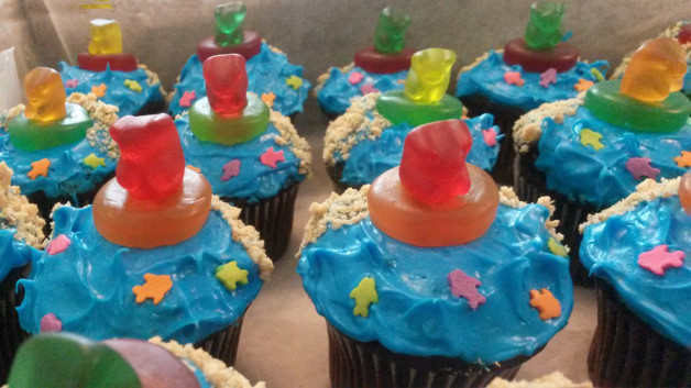 cupcakes decorated with blue 'sea' frosting, has sand and gummy bears in lifesavers